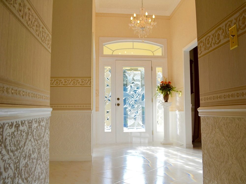 Entryway finished with patterned wallpaper and a decorative border above the wainscot